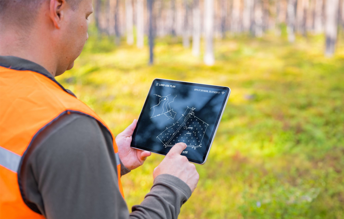 A land surveyor using a tablet in the field for urban planning and infrastructure projects.